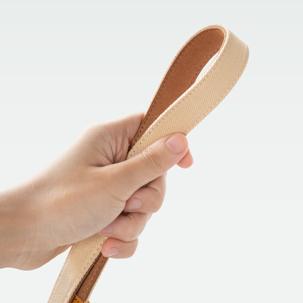Hand holding the TTArtisan beige webbing strap loop
