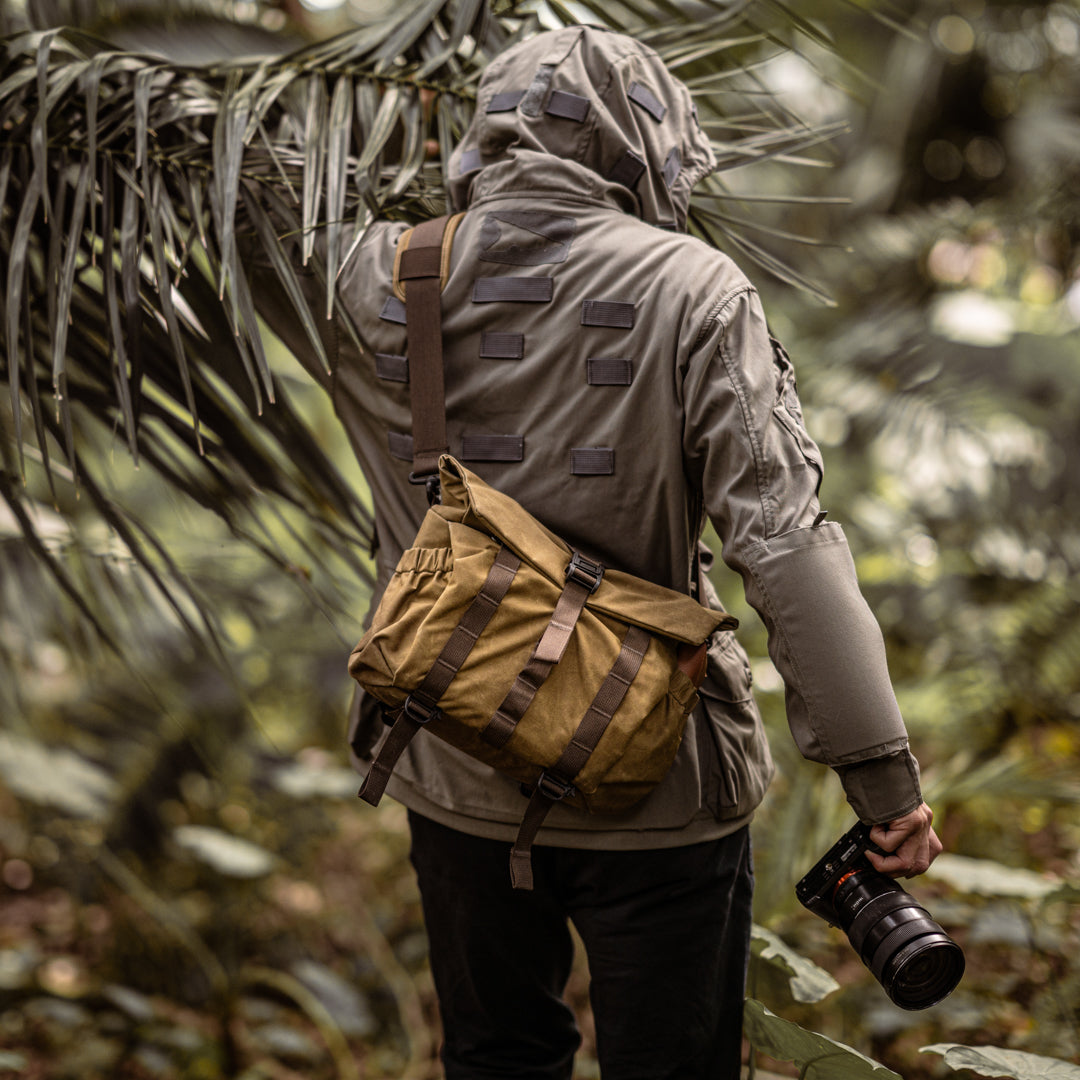 Photographer walking through a jungle with the Wotancraft Pilot khaki bag