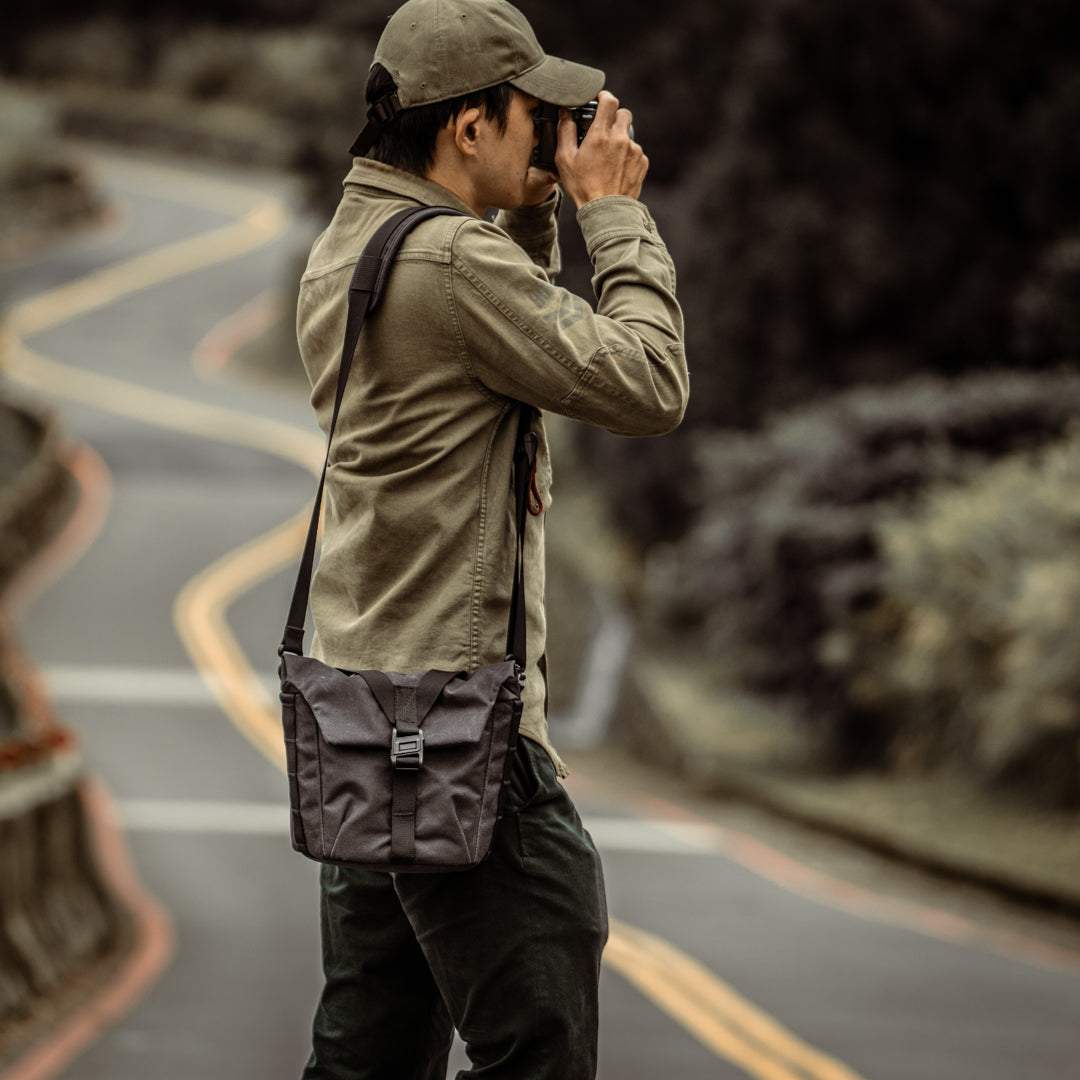 Man taking a photo with the Wotancraft Pilot 3.5L black bag at his hip