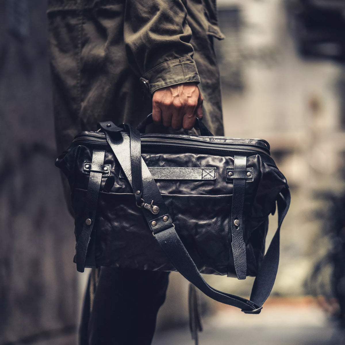 Man carrying the Wotancraft Lightning Rider black leather bag by the handle in an alley