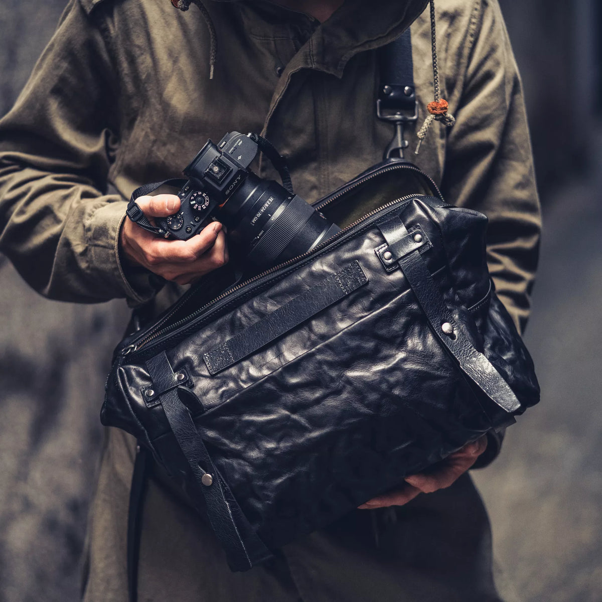 Man with a Sony camera wearing the Wotancraft Lightning Rider black leather bag