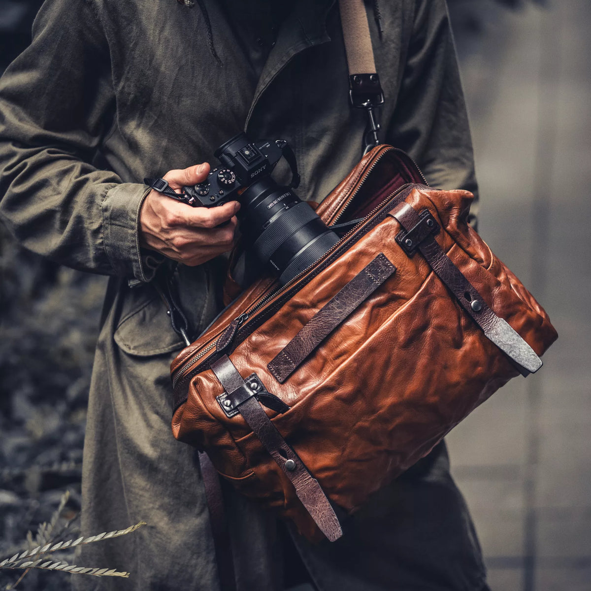 Man with a Sony camera wearing the Wotancraft Lightning Rider brown leather bag