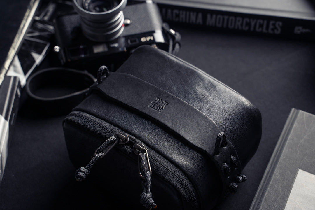 Wotancraft black leather pouch on a desk next to a Leica M6, from above