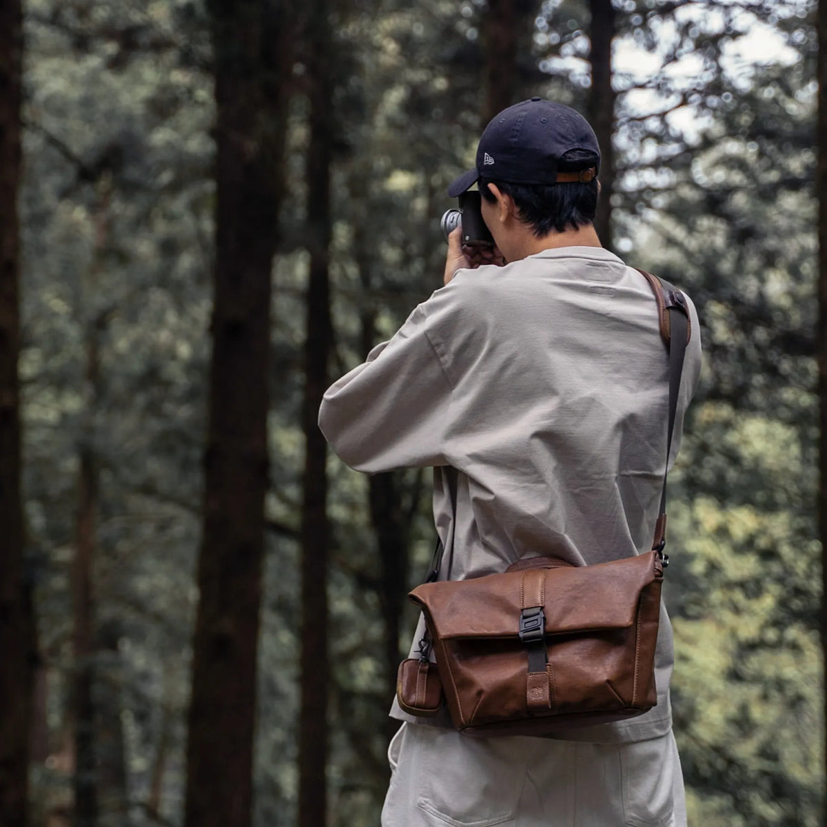 Photographer in a forest wearing the Wotancraft Pilot brown leather bag