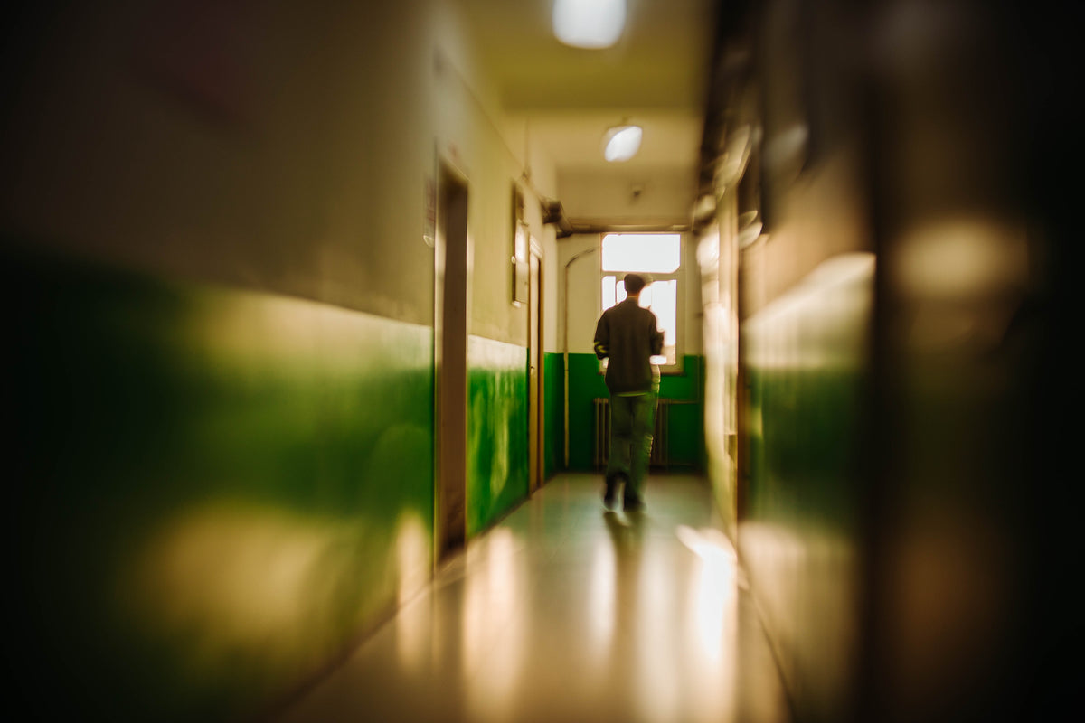 Man walking down a green corridor with dreamy edge blur, Floral Bloom lens sample