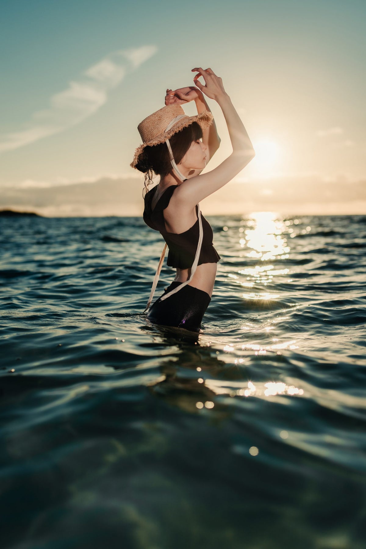 Woman in a straw hat standing in the sea at sunset, sample from the Voigtlander Nokton 40mm f/1.2