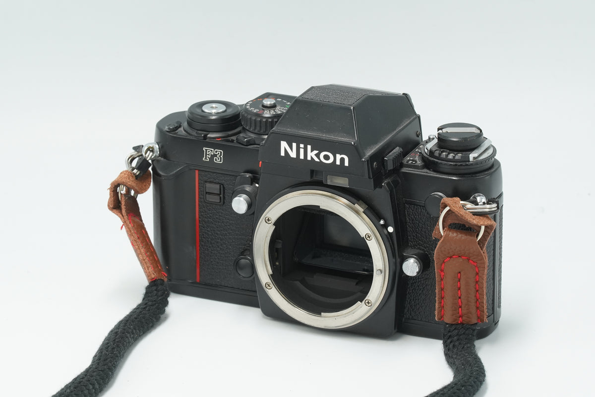 Nikon F3 black 35mm SLR body, front three-quarter view with strap