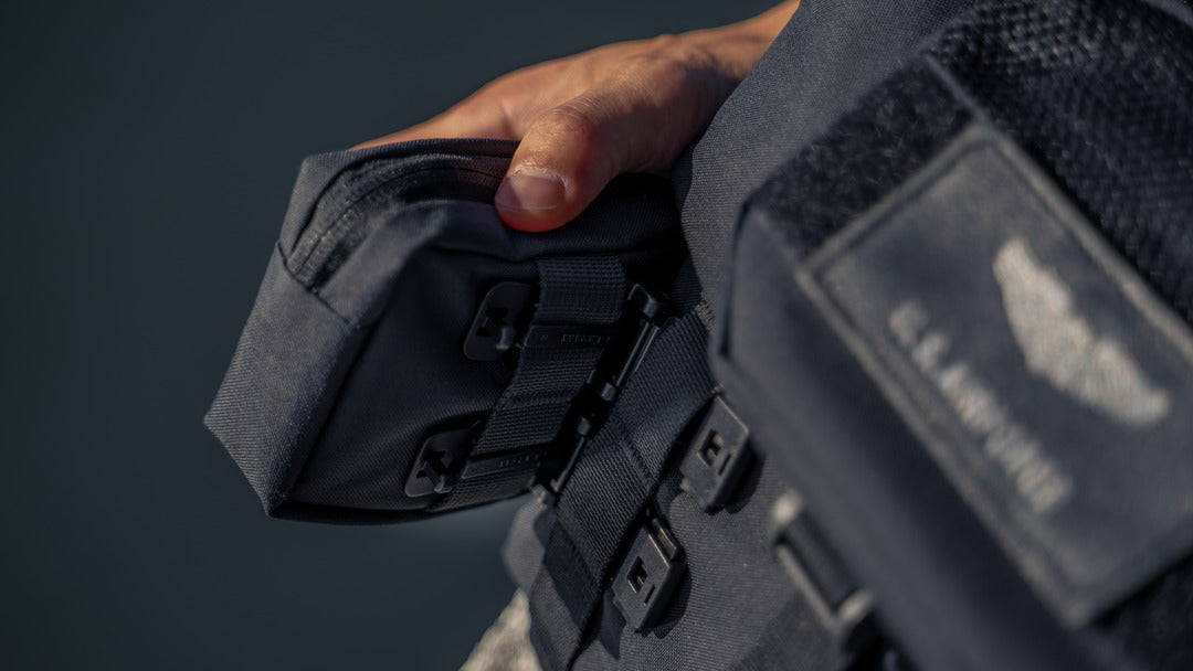 Hand holding a Wotancraft Armor pocket clipped to a bag strap
