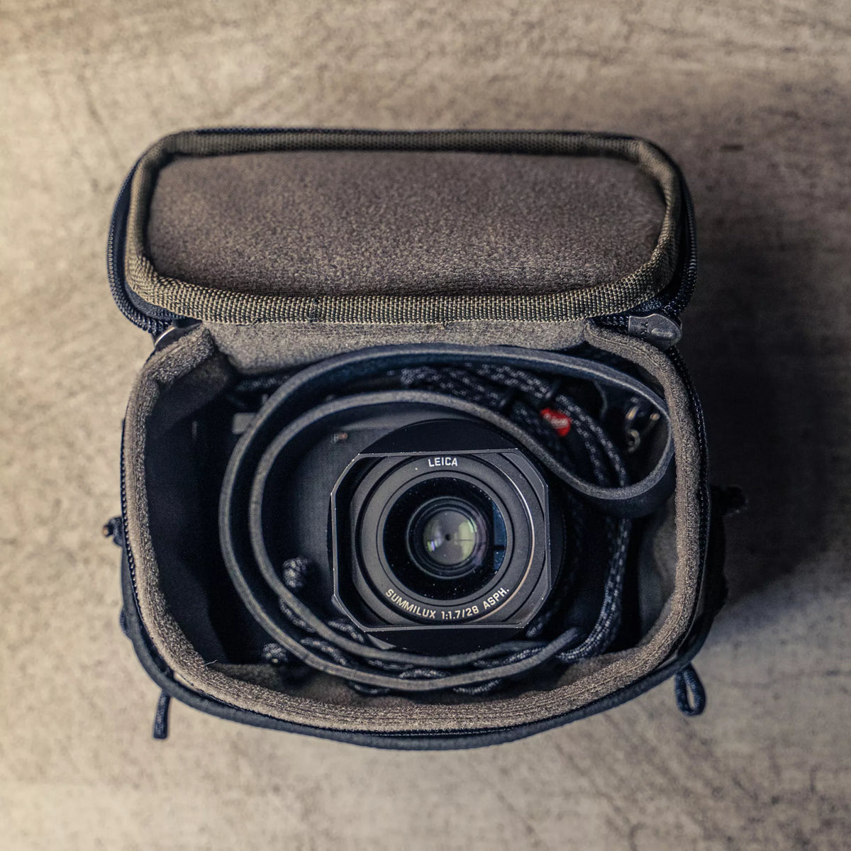 Wotancraft black canvas pouch open with a Leica Q and strap coiled inside