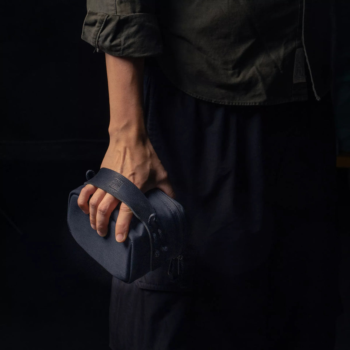 Hand carrying a Wotancraft camera pouch by its strap