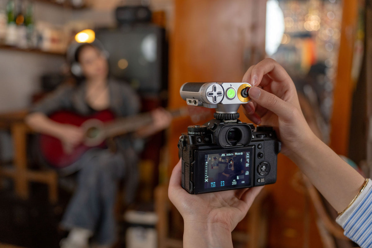 Hands holding a Fujifilm X-T camera with the Viltrox Vintage Z1+ flash in a cafe