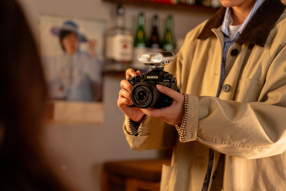 Woman photographing with a Fujifilm camera and the Viltrox Vintage Z1+ flash