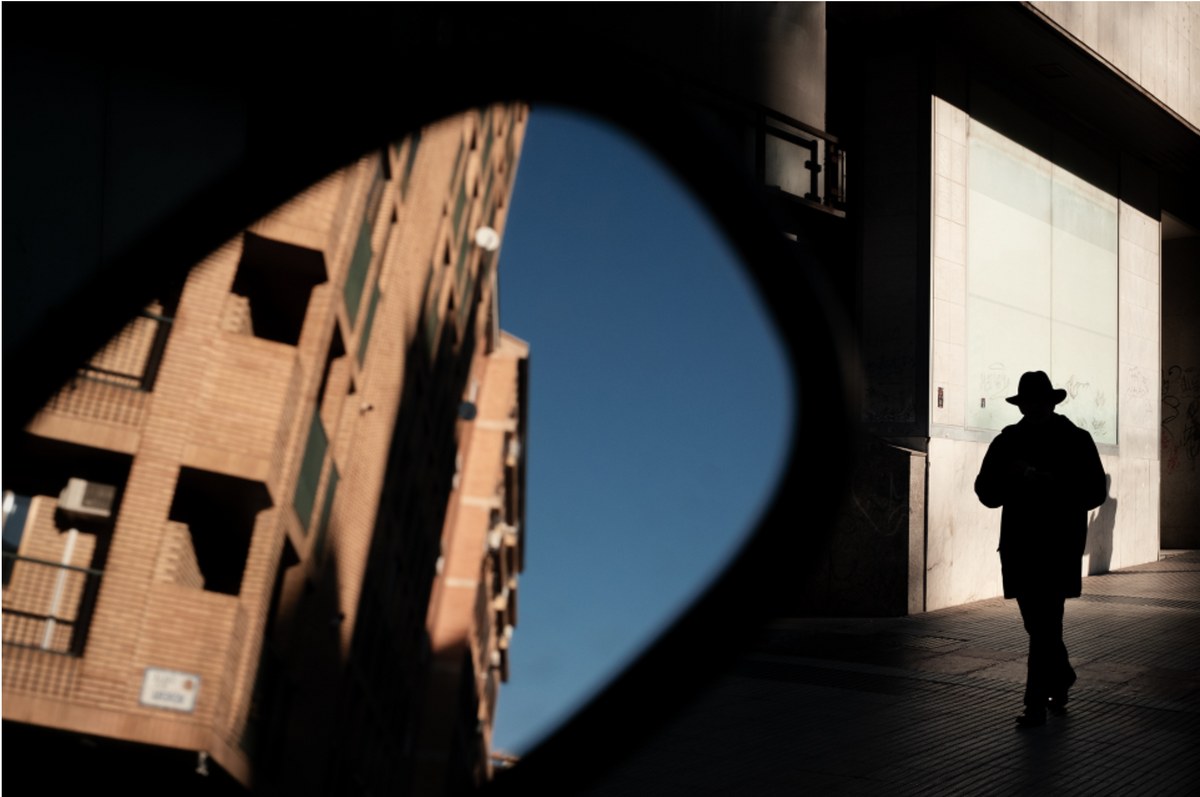 Man in a hat walking past a building, street sample from the Thypoch Simera 35mm f/1.4