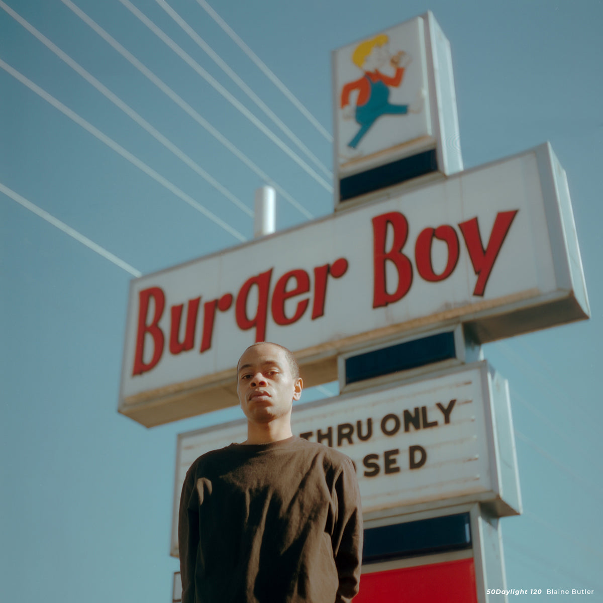 Young man under a Burger Boy sign, sample shot on CineStill 50D 120