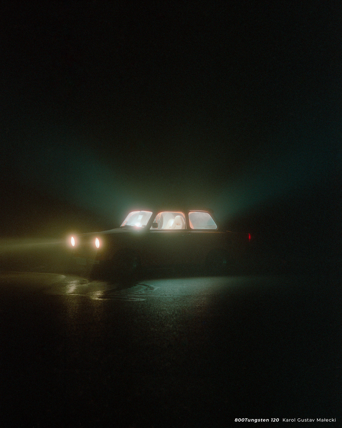 Car with glowing windows in fog at night, sample shot on CineStill 800T