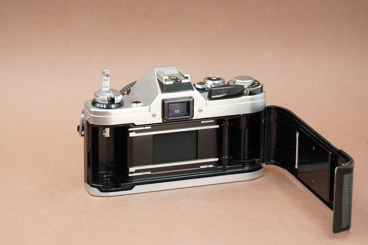 Canon AE-1 film camera with the back open, showing the film chamber