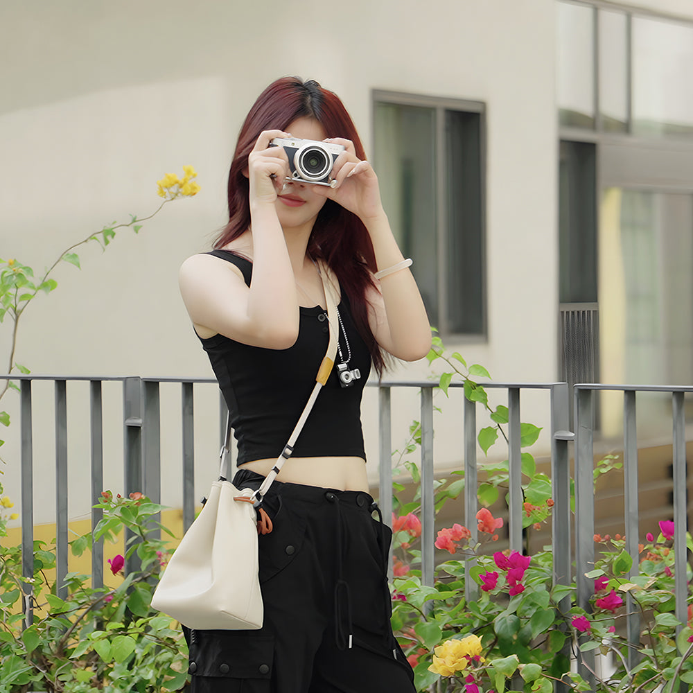 Woman taking a photo with the TTArtisan cream drawstring bag on her shoulder