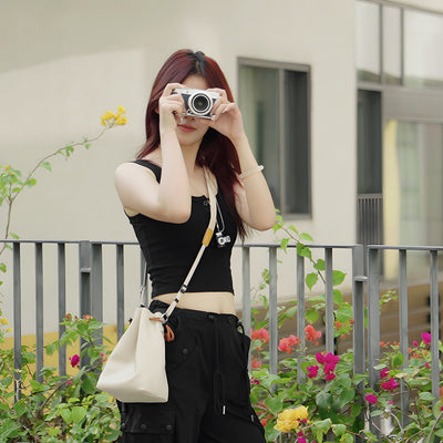 Woman taking a photo with the TTArtisan cream drawstring bag on her shoulder