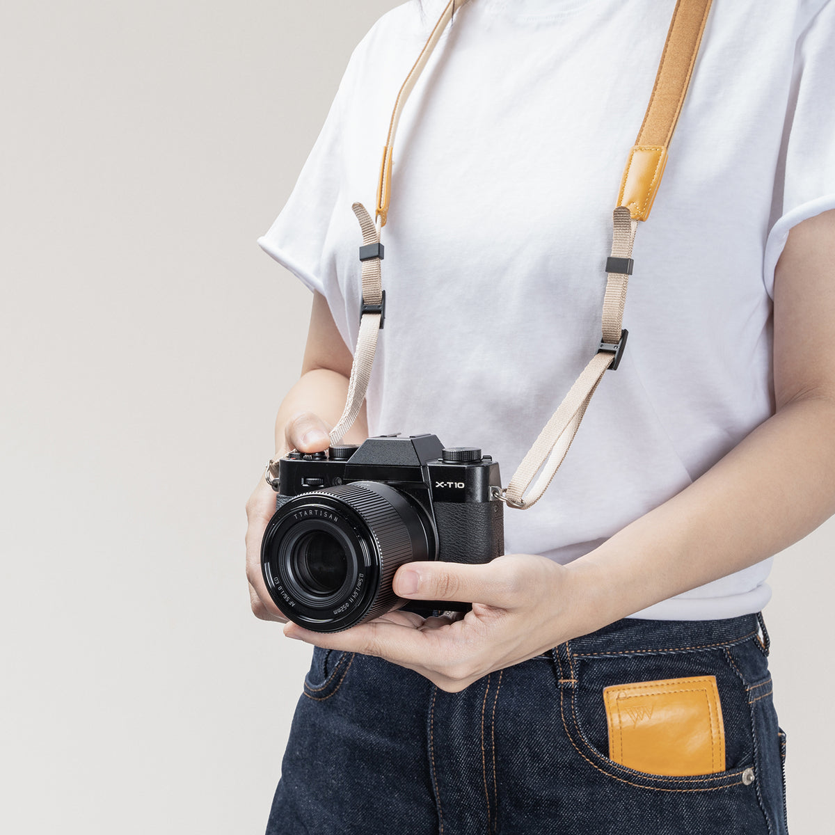 Woman wearing a Fujifilm X-T10 on the TTArtisan beige strap