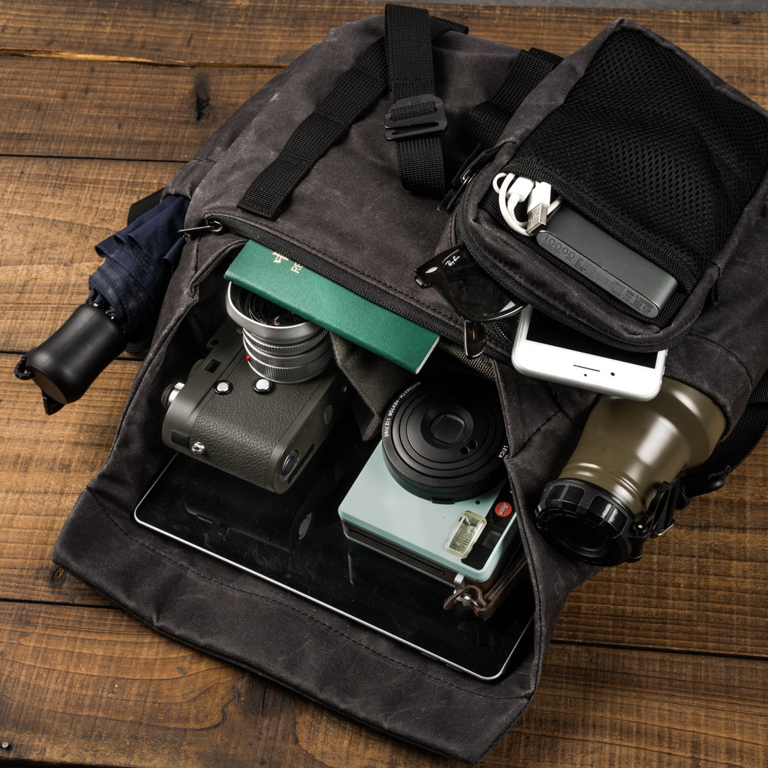 Wotancraft Pilot 7L charcoal bag open with Leica camera, instant camera, tablet and passport