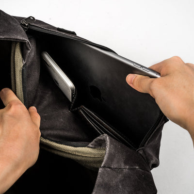 Hands sliding a tablet into the Wotancraft Pilot bag rear laptop sleeve