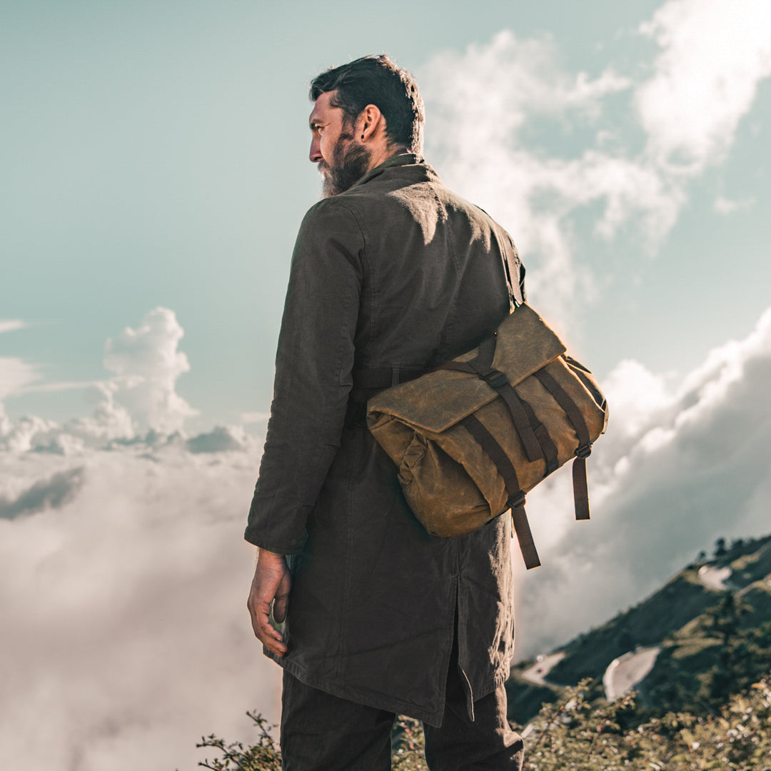 Bearded man on a mountain top wearing the Wotancraft Pilot 10L khaki bag