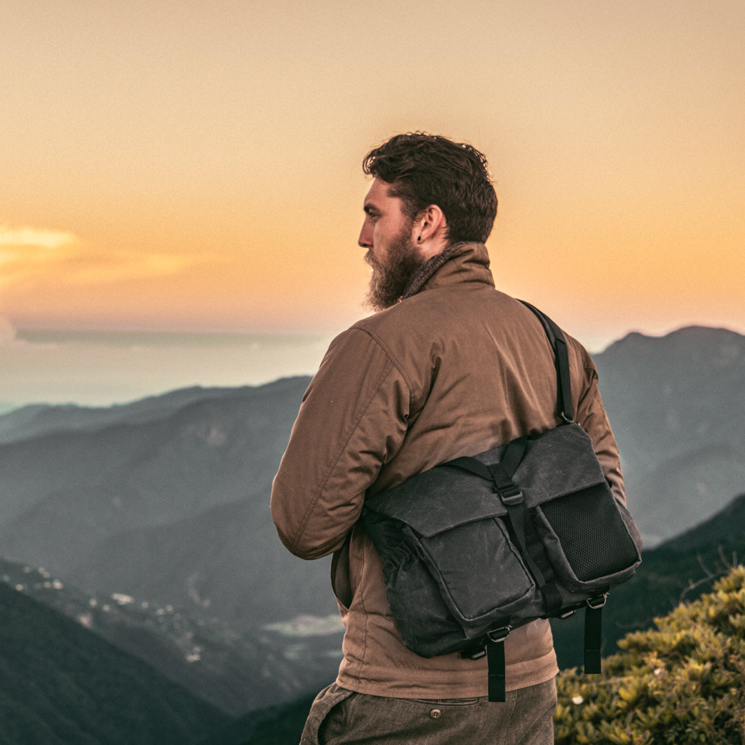 Bearded man at sunset in the mountains wearing the Wotancraft Pilot 10L charcoal bag