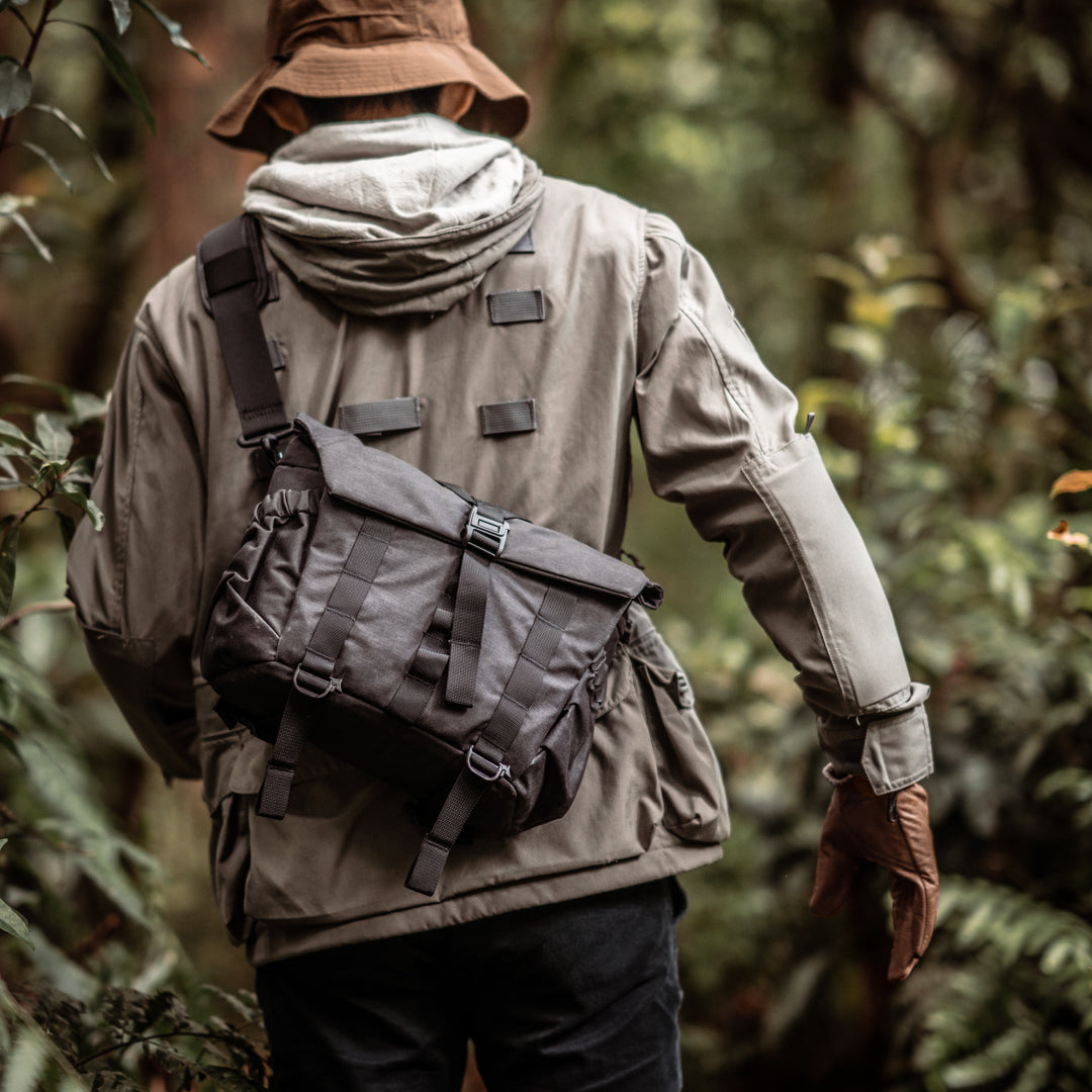 Man in a forest wearing the Wotancraft Pilot 7L charcoal bag, rear view