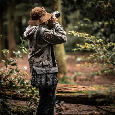 Photographer with a telephoto lens wearing the Wotancraft Pilot 7L charcoal bag