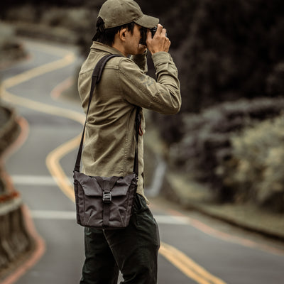 Photographer on a winding road wearing the Wotancraft Pilot 3.5L black bag