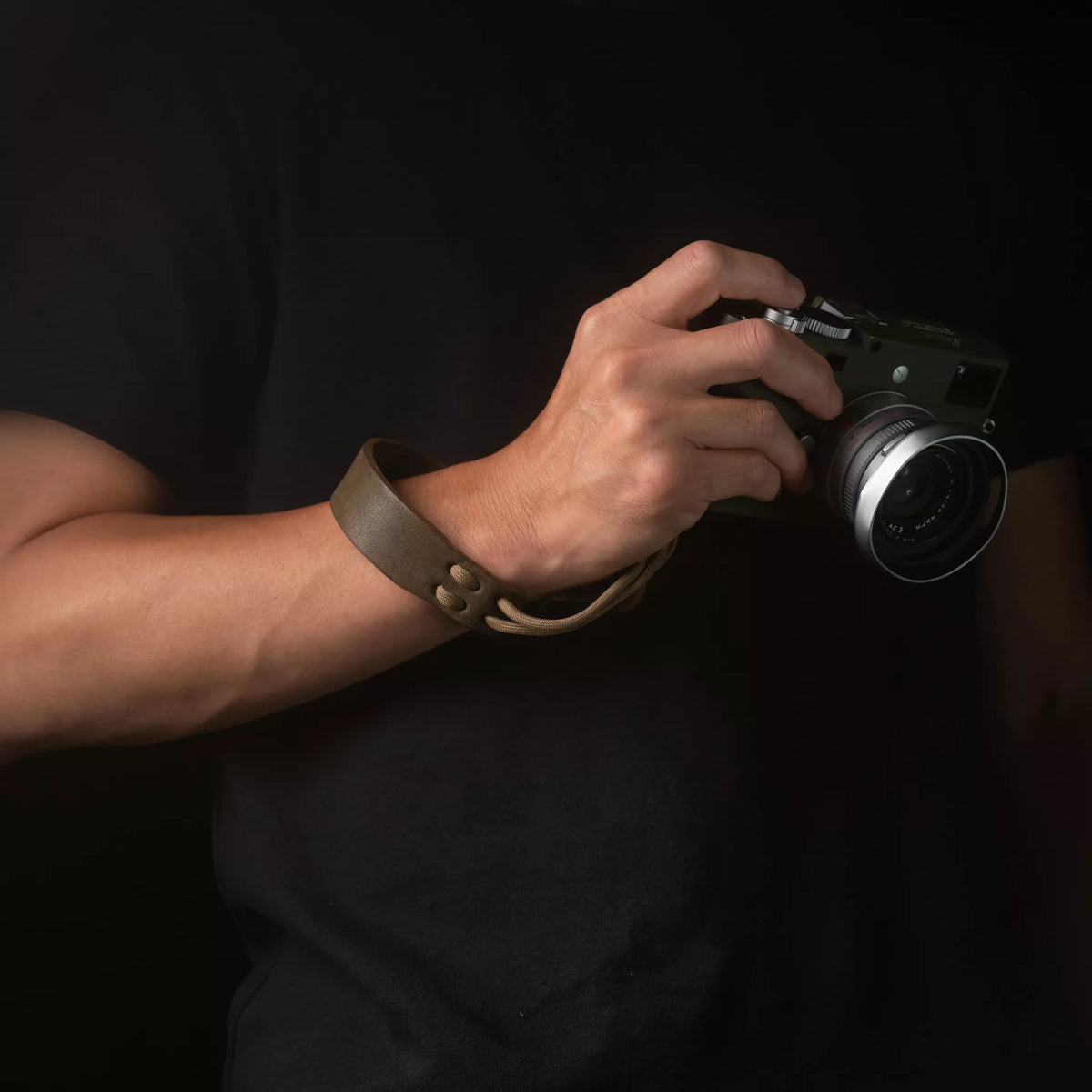 Man holding an olive Leica with the Wotancraft Parashooter olive wrist strap