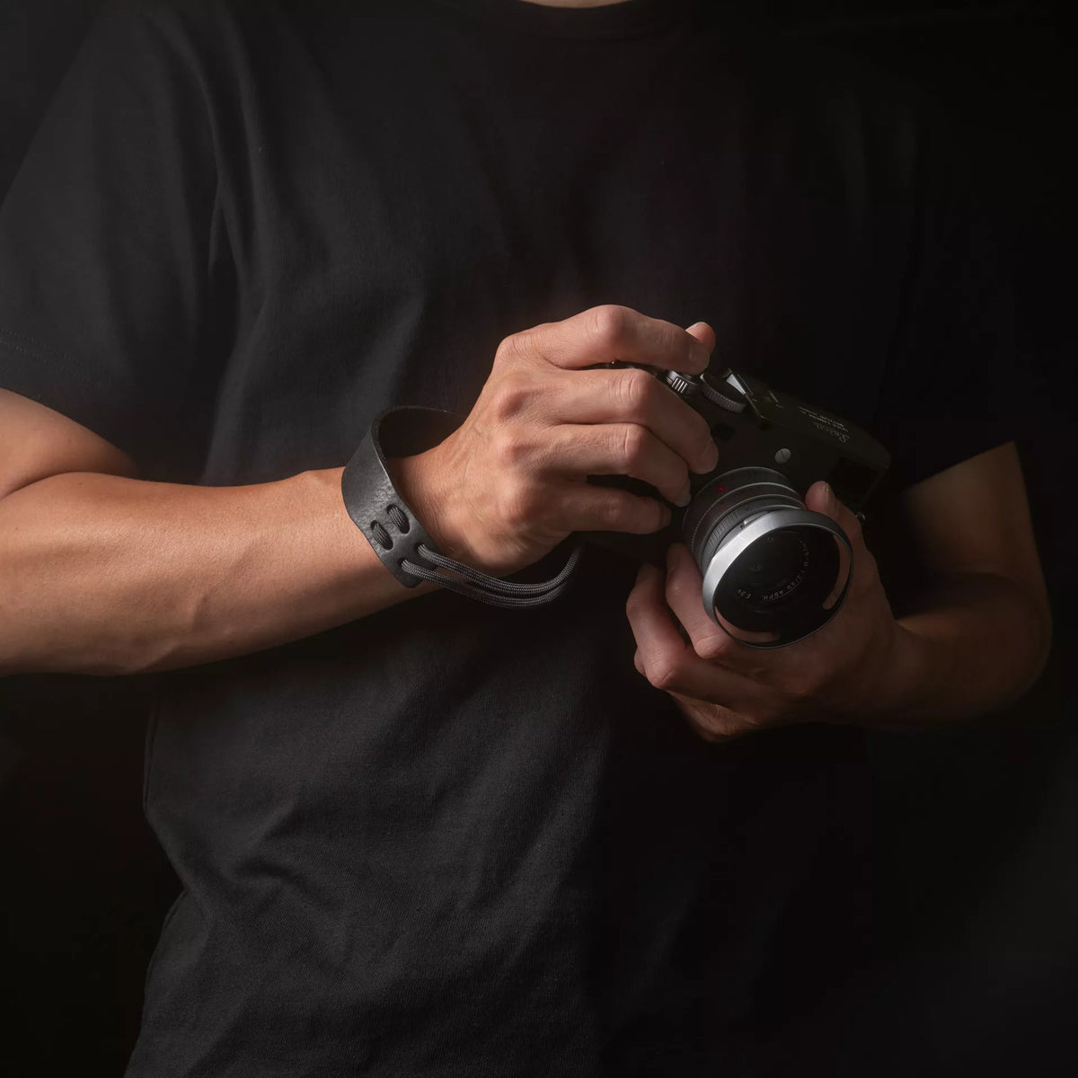 Man holding a Leica camera with the Wotancraft Parashooter black wrist strap