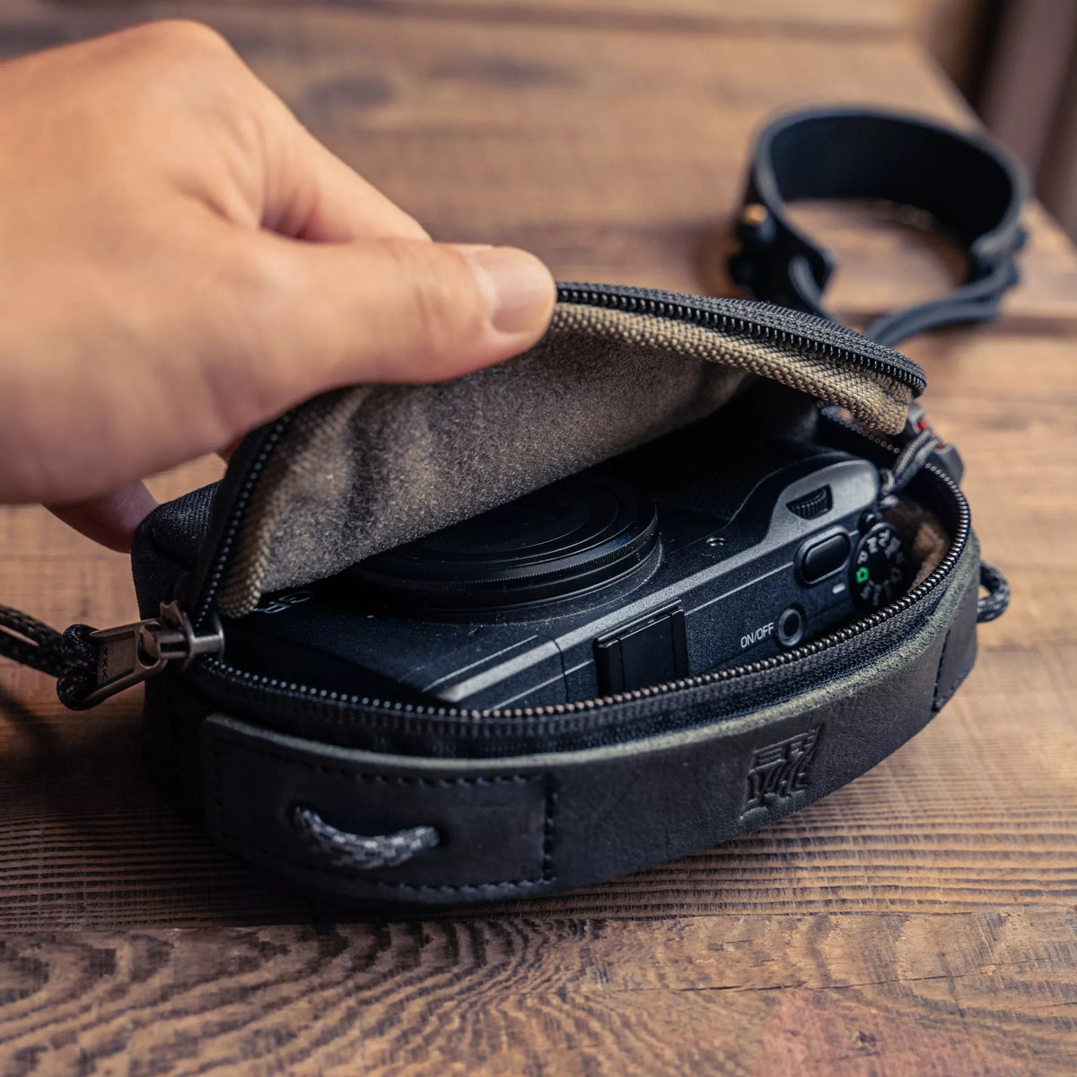 Hand opening the Wotancraft small black canvas pouch with a Ricoh GR inside
