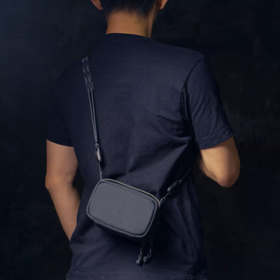 Man wearing the Wotancraft black canvas camera pouch on a strap, rear view