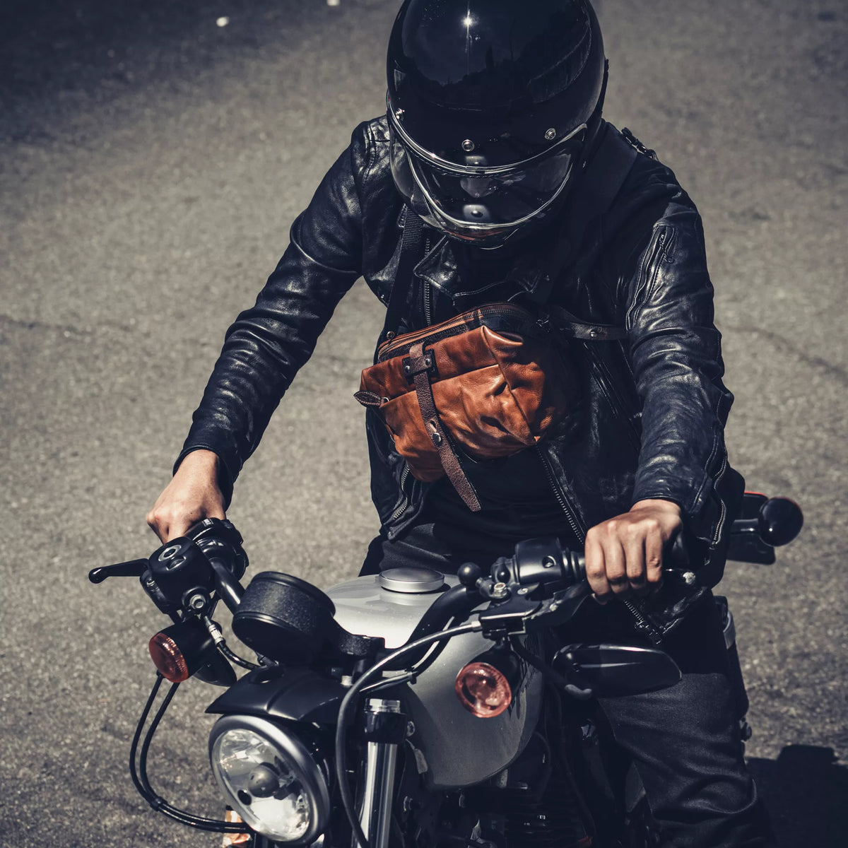 Motorcyclist wearing the Wotancraft Mini Rider brown leather bag across the chest