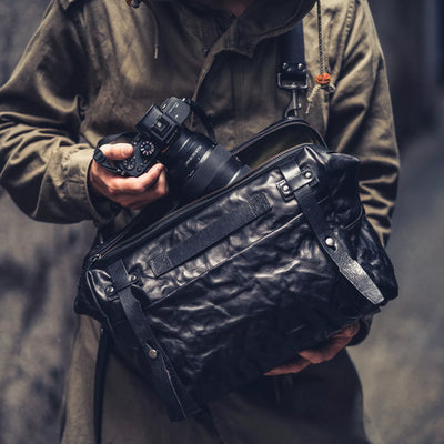 Man with a Sony camera wearing the Wotancraft Lightning Rider black leather bag