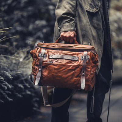 Man carrying the Wotancraft Lightning Rider brown leather bag by the handle