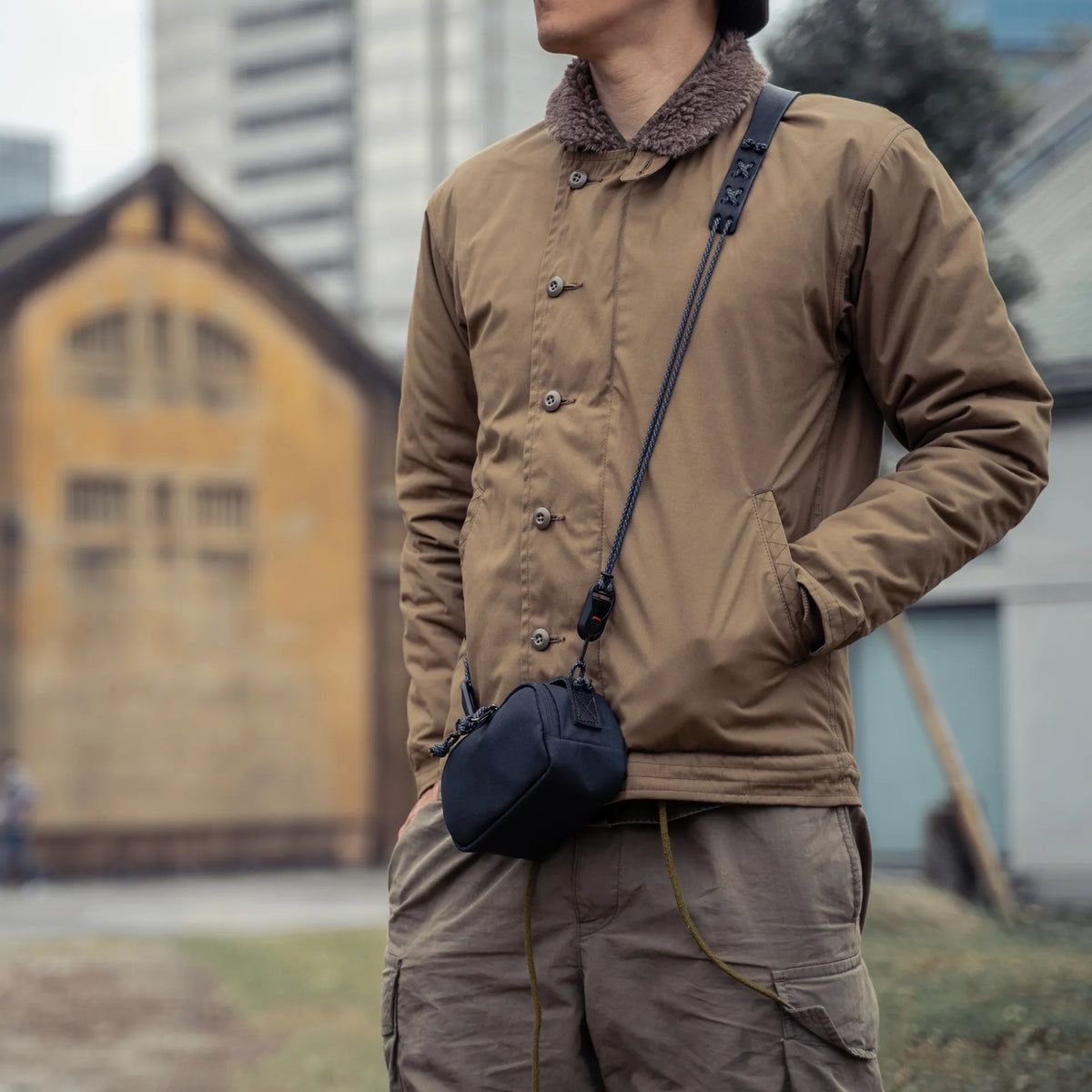 Man in a khaki jacket wearing the Wotancraft black canvas pouch on a strap