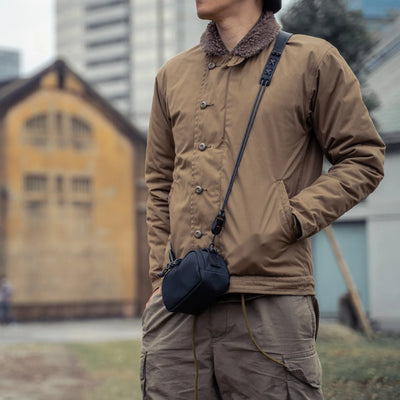 Man in a khaki jacket wearing the Wotancraft black canvas pouch on a strap