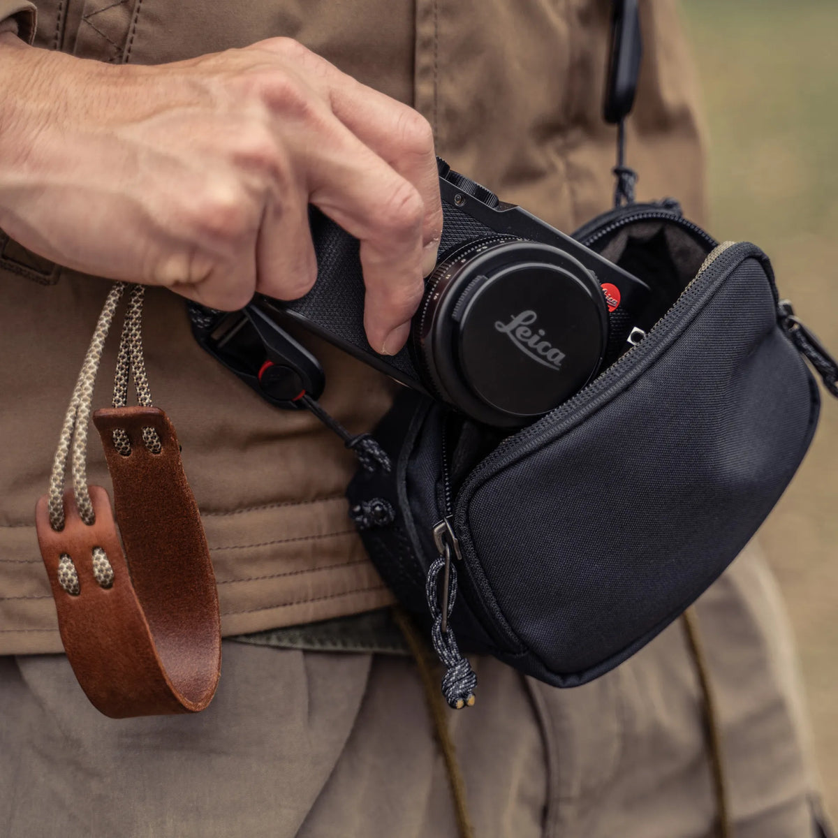 Man taking a Leica D-Lux out of the Wotancraft black canvas medium pouch