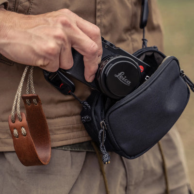 Man taking a Leica D-Lux out of the Wotancraft black canvas medium pouch