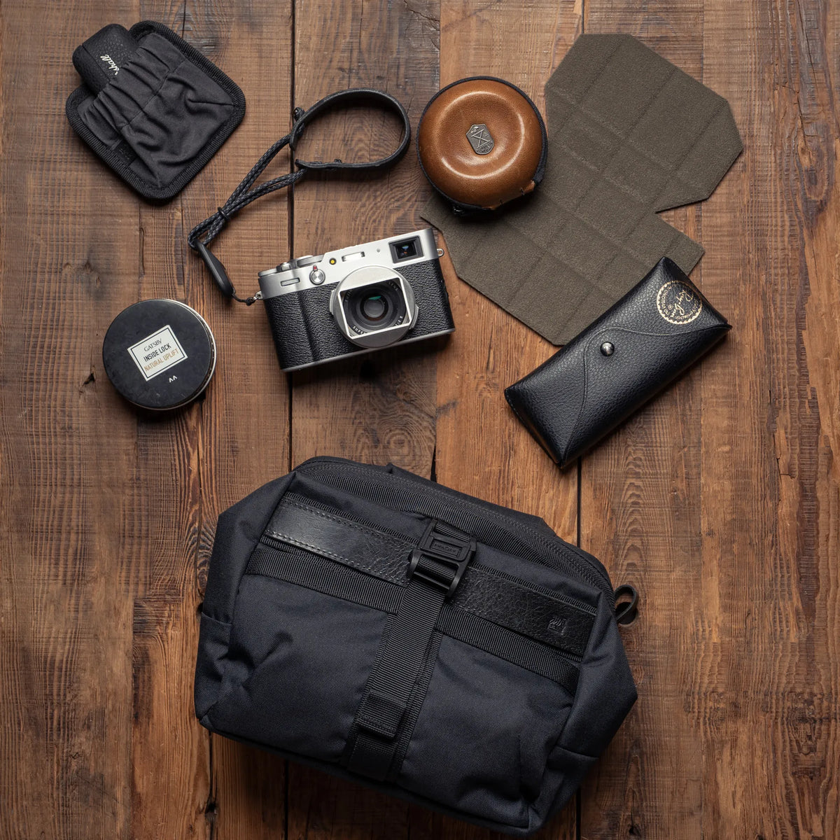 Wotancraft Mini Rider v2 black sling with Fujifilm X100 camera and accessories laid out