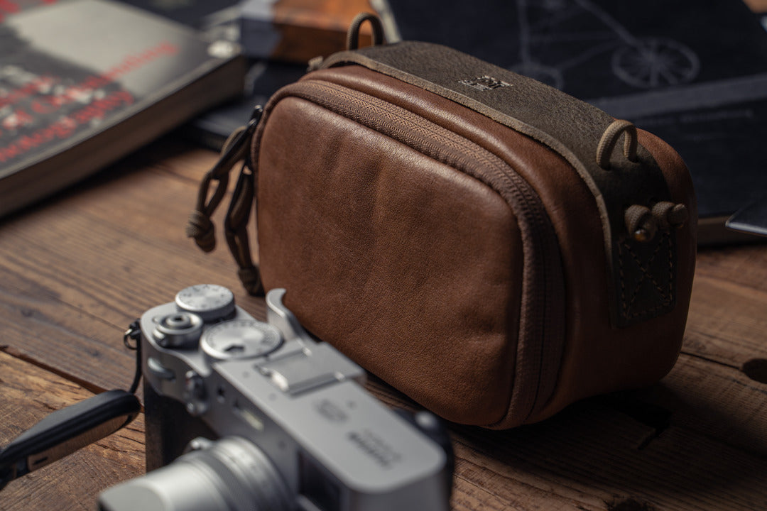 Wotancraft brown leather camera pouch next to a silver Fujifilm X100