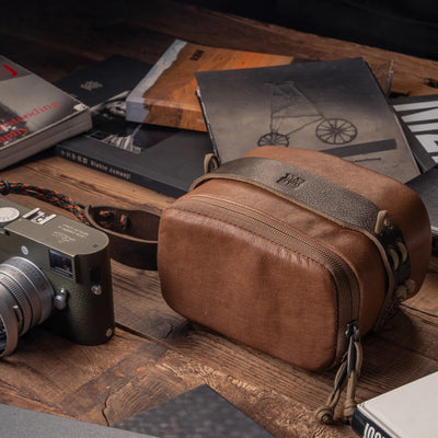Wotancraft brown leather pouch beside an olive Leica M on a desk with books