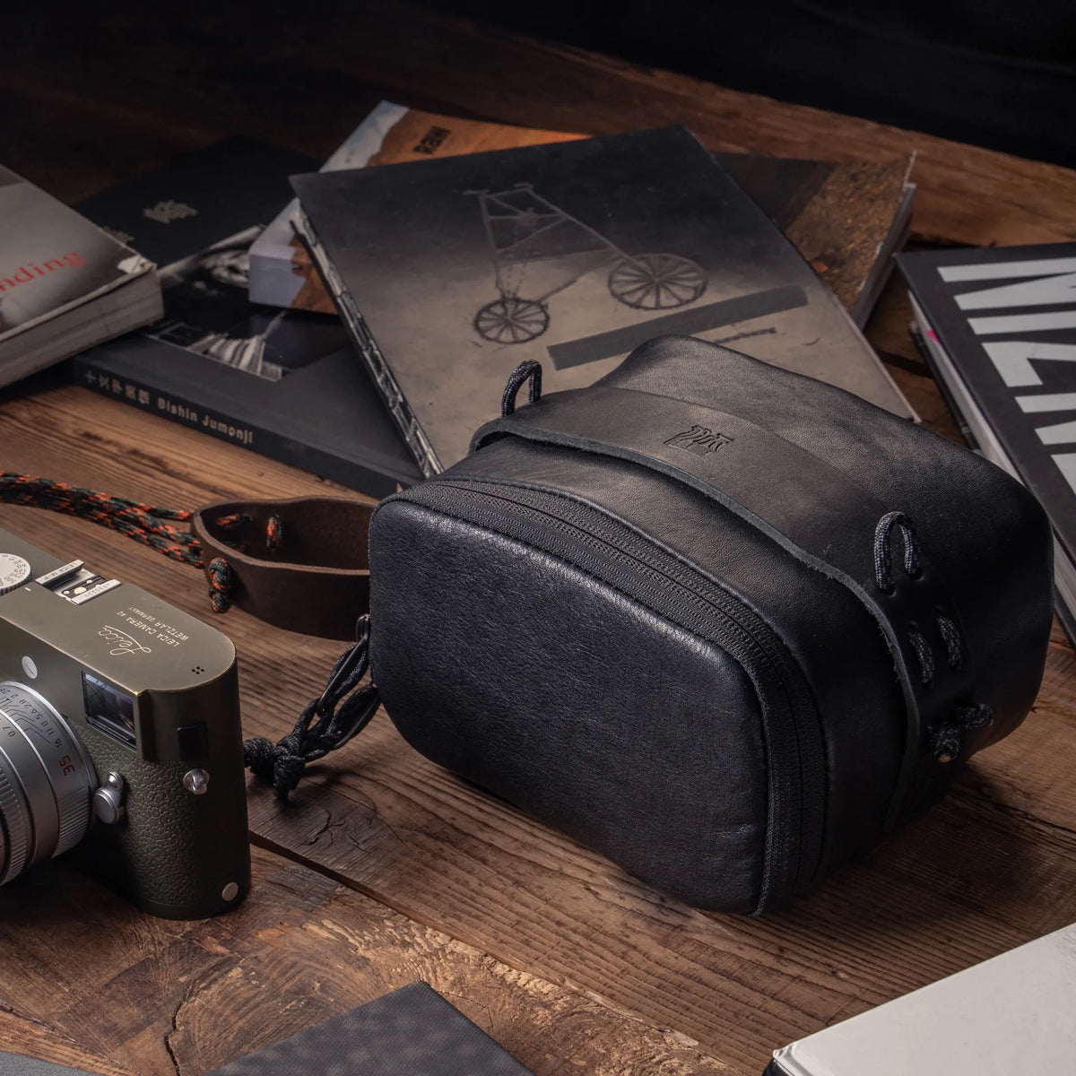 Wotancraft black leather pouch beside an olive Leica M on a desk with books