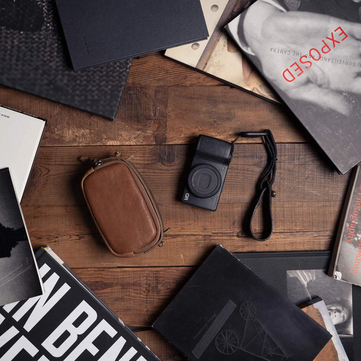 Wotancraft brown leather small pouch and Ricoh GR among photo books, from above