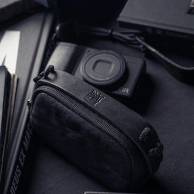 Wotancraft black leather small pouch with embossed logo next to a Ricoh GR