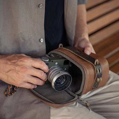Man taking an olive Leica M out of the Wotancraft brown leather pouch