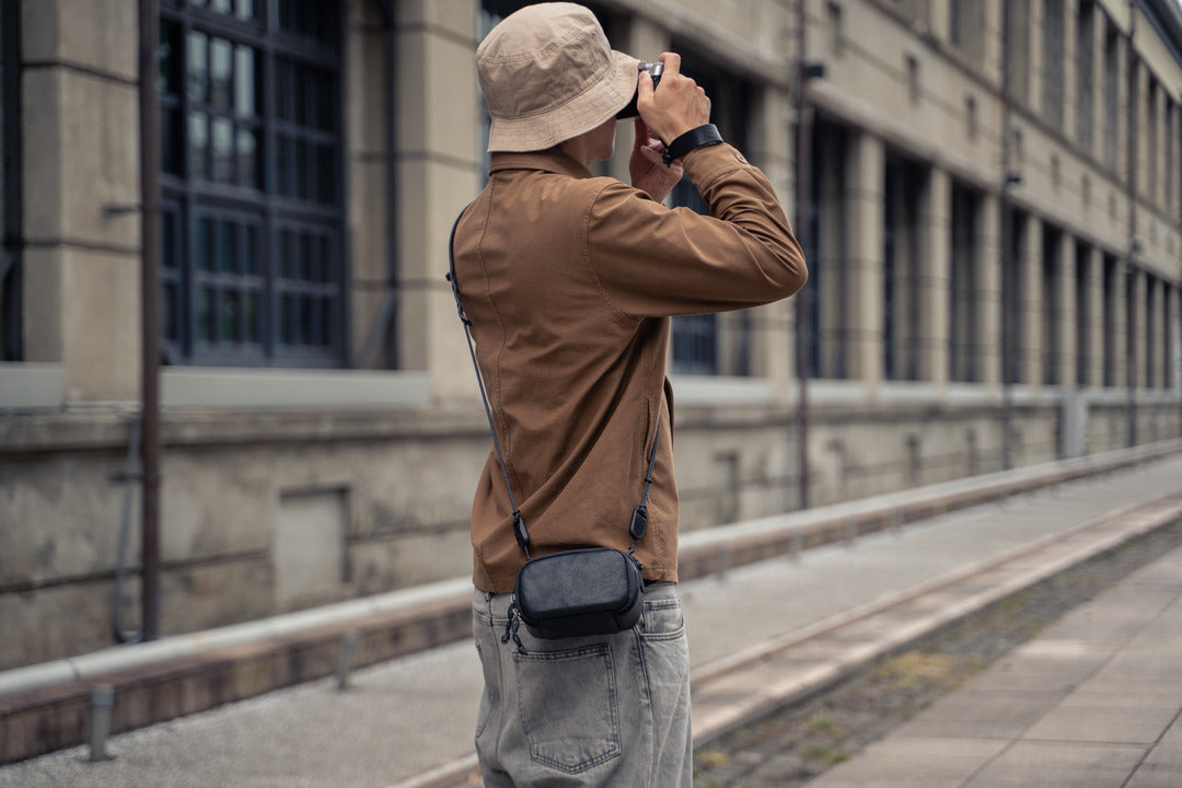 Photographer on a street with a black Wotancraft leather pouch on a strap