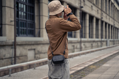 Photographer on a street with a black Wotancraft leather pouch on a strap